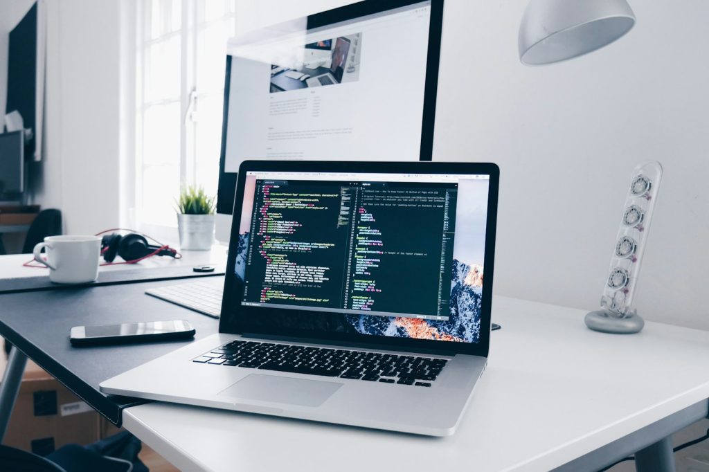 Laptop showing website code next to a cup of coffee