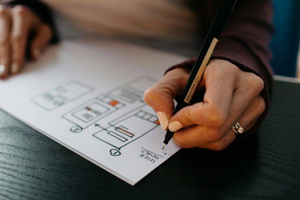 Hands arranging paper wireframes of mobile app screens